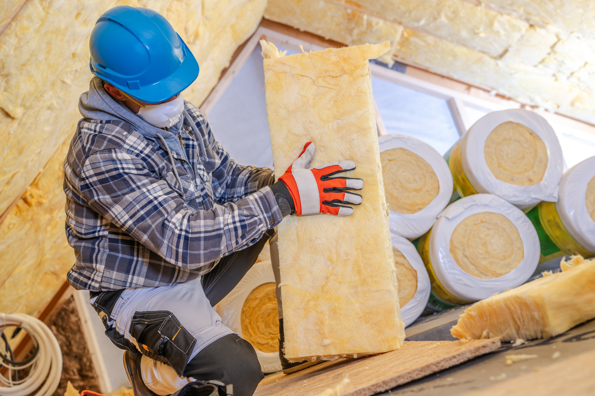 Worker Installing Mineral Wool Insulation in a Residential Attic